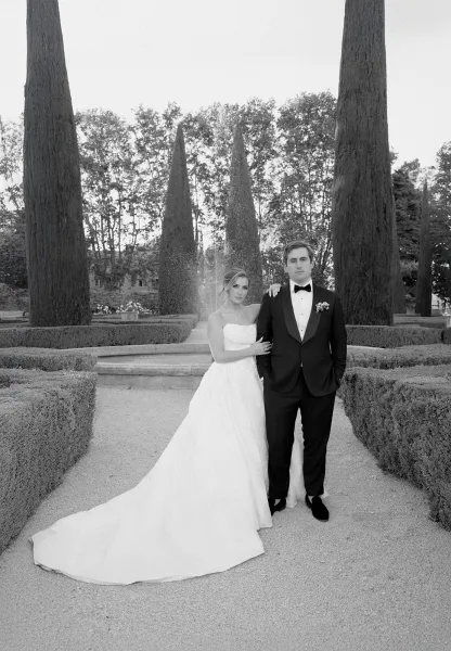 Couple portrait, a black and white couple portrait with the bride in a strapless gown beside a fountain in a formal garden with manicured hedges.