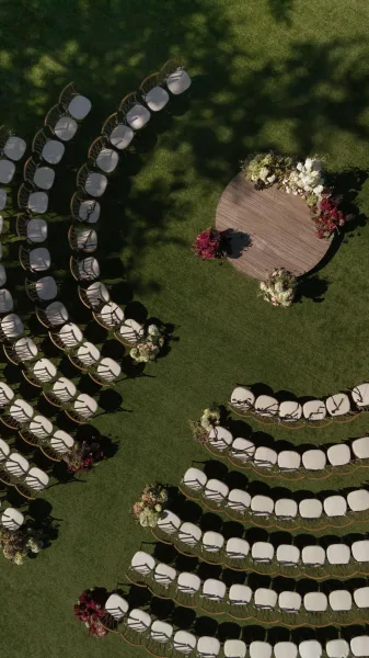 Ceremony setup with outdoor ceremony seating in a curved spiral around a round wooden stage, with hydrangea florals on a green lawn