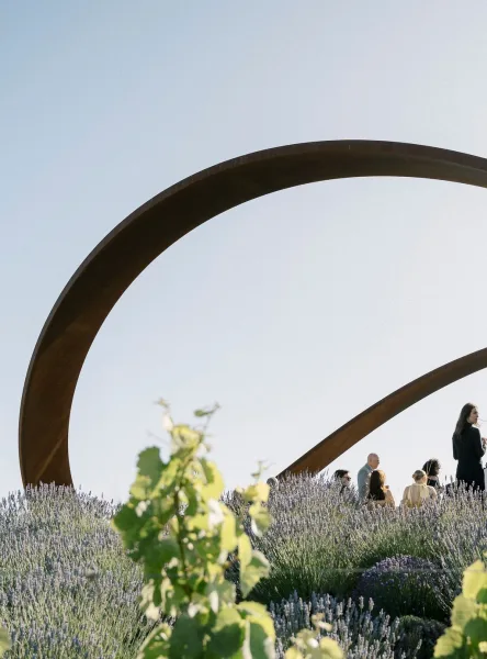 Ceremony setup with modern ceremony arch, a metal circular arch accented with lavender on a hillside with guest seating and open sky