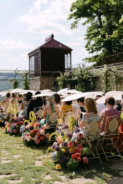 Ceremony seating decor with wrought iron chairs for outdoor ceremony seating on a garden lawn, backed by trees and a distant hillside.