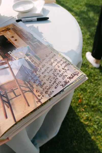Wedding guest book open for signatures as a guest book alternative, with a pen beside it and a grass lawn softly filling the background.