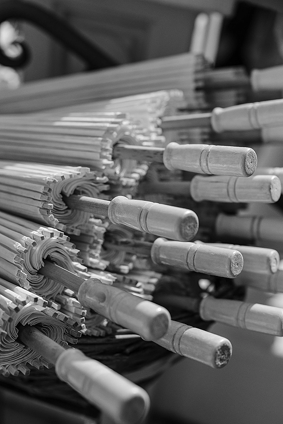 Wedding parasols and paper parasol favors stacked on a table, showing white paper canopies with wooden handles ready for guests