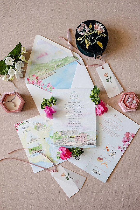 Invitation suite wedding invitation flat lay with watercolor cards, vellum wrap and ribbon, rings and jewelry on a linen backdrop