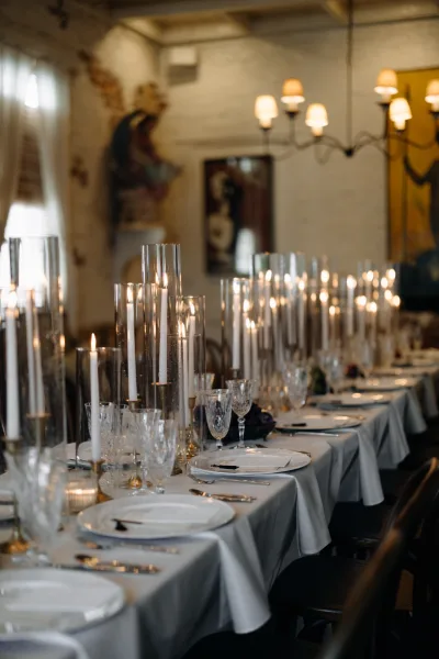 Reception tablescape with wedding head table decor featuring taper candles, gold candlesticks, crystal glassware in a chandelier-lit dining room