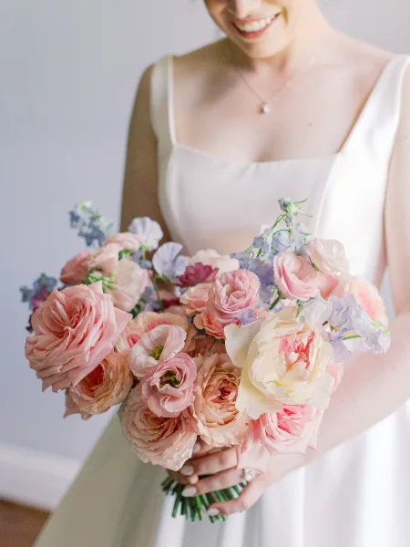 Bridal bouquet, a pink rose bouquet in soft pink tones, held close with a subtle glimpse of an engagement ring.