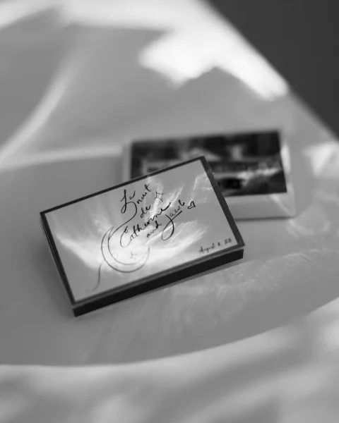 Wedding place cards with calligraphy place cards and photo escort cards arranged on a white tabletop, lit by soft light and shadow