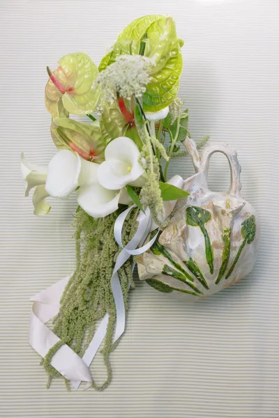 Bridal bouquet with calla lily wedding bouquet details, anthurium and greenery with trailing amaranthus and white ribbon on striped backdrop