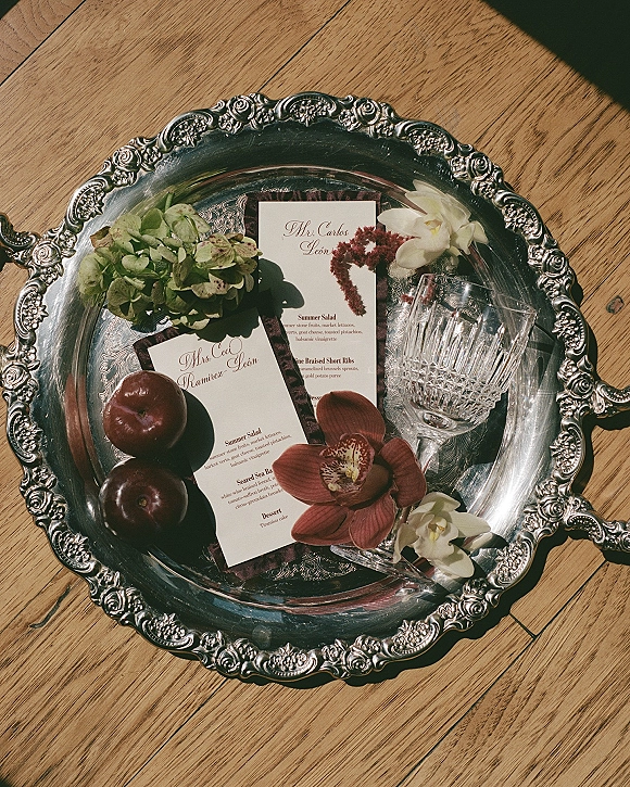 Wedding menu cards with calligraphy wedding menu styled on an ornate silver tray with orchids, fruit, crystal coupes, and burgundy ribbon in sunlit shadows