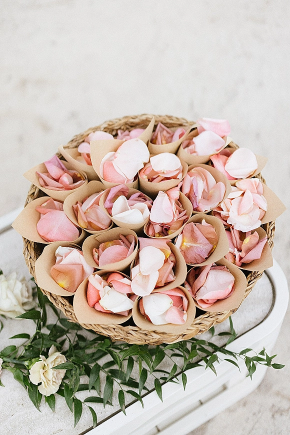Flower petal cones for wedding petal toss cones filled with pink and white rose petals in a woven basket on a white table