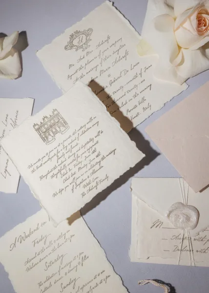 Wedding invitation suite of handmade paper invitations arranged neatly with a wax seal accent, set on a textured linen tabletop.