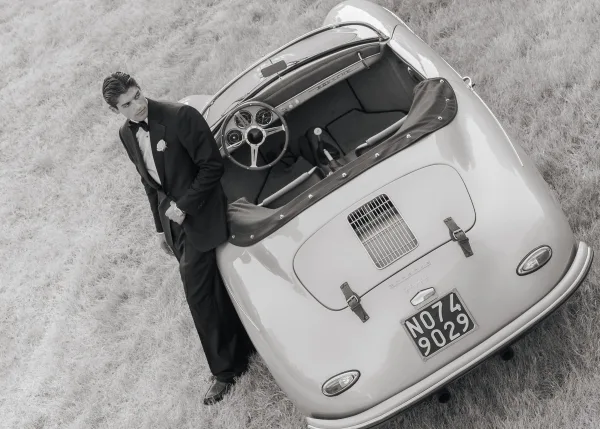 Groom portrait featuring a groom with classic car, standing by a vintage convertible in formal attire.