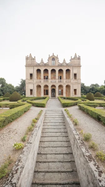 Wedding venue exterior of a villa wedding venue with a grand stone staircase leading up to a symmetrical, elegant neutral facade.