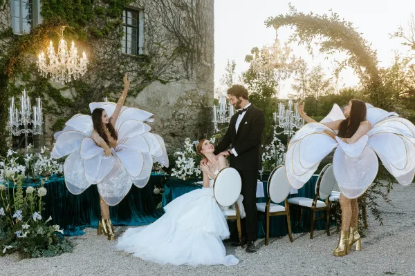Couple portrait of bride in strapless ball gown and groom in black tuxedo by an ivy-covered stone wall at sunset courtyard