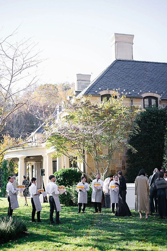 Wedding cocktail hour with wedding passed drinks on trays, champagne flutes and orange spritzes served on a sunny estate lawn by staff