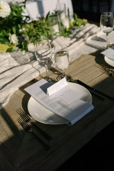Wedding place setting with printed wedding menu, paired with black flatware on a wooden table, arranged neatly with a clean, modern feel.