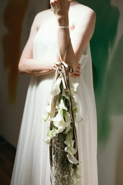Bridal bouquet, a sculptural calla lily bouquet with trailing Spanish moss adding texture and movement, styled for a modern, minimalist look.