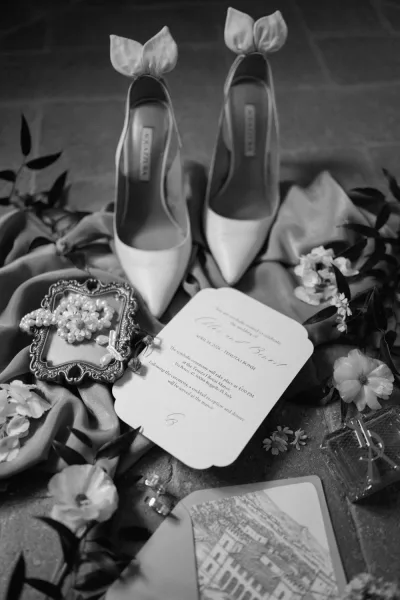 Invitation suite in a wedding invitation flat lay, offering invitation styling ideas with bridal heels arranged on a textured stone floor.