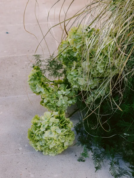 Floral arrangement featuring a green hydrangea arrangement, styled low along stone steps on a smooth concrete floor.