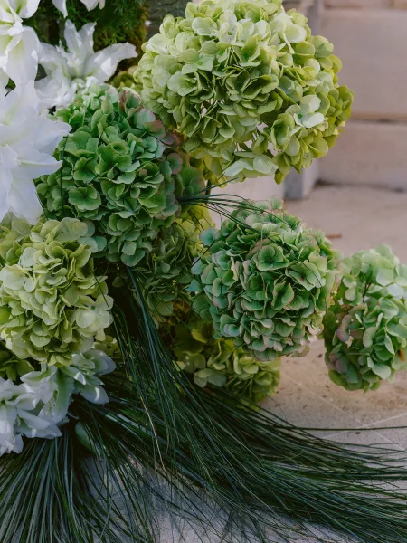 Wedding floral arrangement featuring hydrangea wedding flowers set along stone steps on a concrete floor.