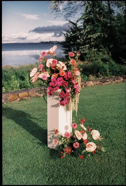 Ceremony floral arrangement with anthurium, styled as outdoor ceremony flowers on a lakeside lawn with trees and a stone wall.