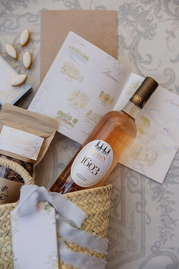 Invitation suite with watercolor wedding invitations, envelopes, RSVP and map cards, wax seals, ribbon, and cookies on a patterned tablecloth