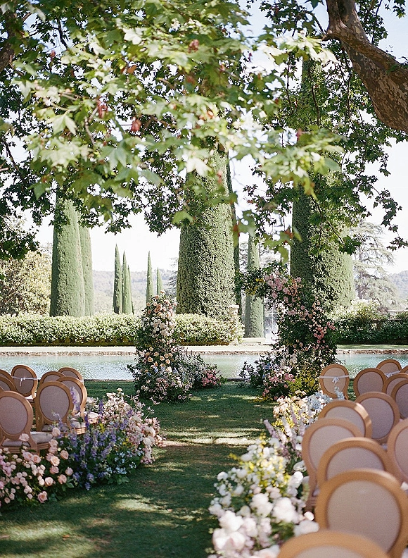 Ceremony aisle design with outdoor wedding ceremony setup, asymmetrical floral arch and meadow aisle flowers beside a reflecting pool lawn