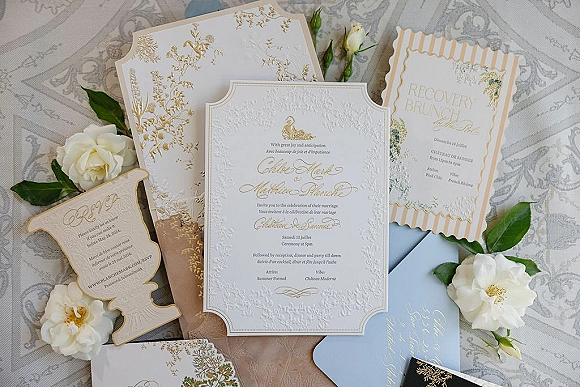 Wedding invitation suite with letterpress wedding invitations and gold foil details, deckled edges, roses and greenery on patterned fabric tablecloth