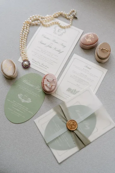 Invitation suite wedding invitation flat lay with pearls, wax seal, ribbon, and velvet ring boxes on a linen fabric backdrop