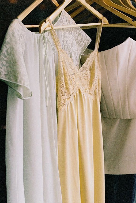 Wedding dress with lace wedding dress bodice and spaghetti straps on hangers, paired with a lingerie slip on a closet rail