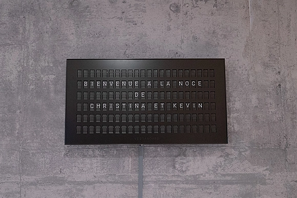 Wedding welcome sign on a black letter board with white letter tiles on a stand against a concrete wall backdrop