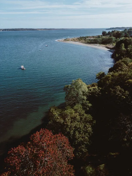 Wedding venue view of a coastal wedding venue overlooking blue ocean water with boats, sandy beach, trees, and a distant horizon