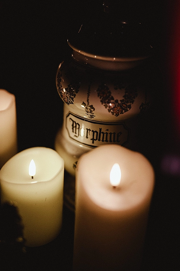 Wedding candle decor with a pillar candle centerpiece, clustered ivory candles beside a floral ceramic vase glowing against a dark background