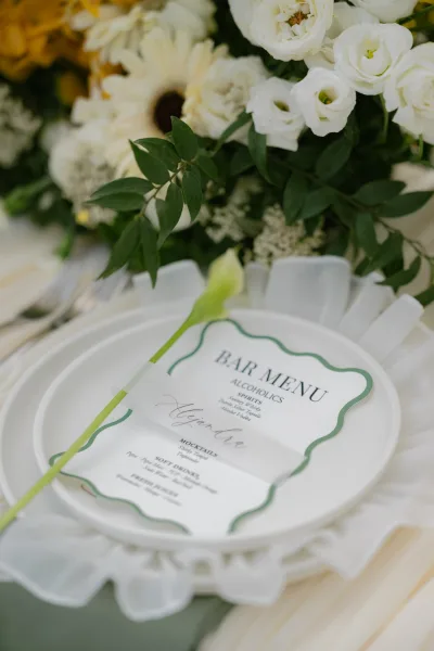 Wedding bar menu and cocktail menu card styled with a single calla lily, framed in green with classic serif typography.