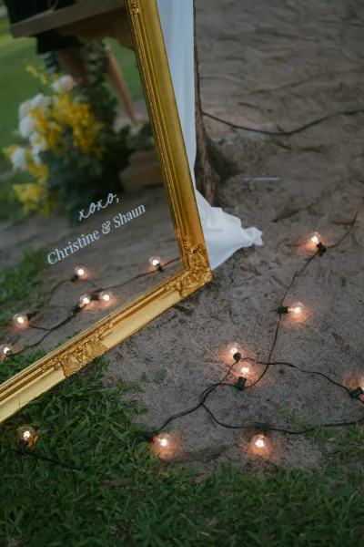 Mirror wedding sign in a gold frame with elegant calligraphy welcomes guests, its reflective surface catching soft ambient light.