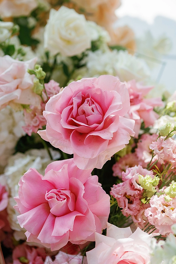 Wedding bouquet with pink rose bouquet accents, mixing blush and white roses, lisianthus, and greenery against softly blurred florals