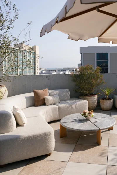 Lounge seating area with wedding lounge seating on a rooftop terrace, featuring a sectional sofa, umbrella, and city skyline backdrop