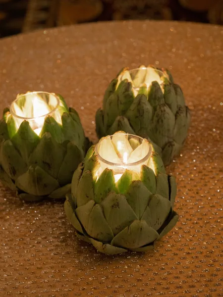 Candle centerpiece with artichoke candle holders casting a warm glow on a sequin tablecloth, styled for an intimate wedding table.