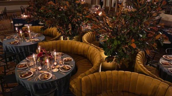 Reception tablescape aglow as a candlelit reception table, with velvet banquettes and florals in a ballroom interior.