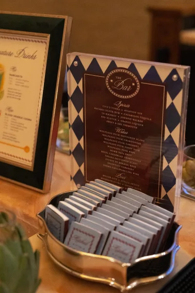 Wedding bar sign featuring a signature drinks menu, styled beside a polished silver tray for a refined, minimal display.
