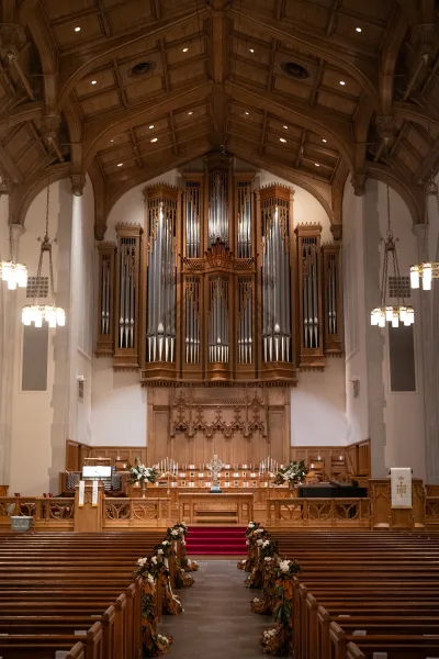 Church ceremony setup with indoor ceremony decor, featuring floral arrangements and an altar framed by a pipe organ and stone columns.