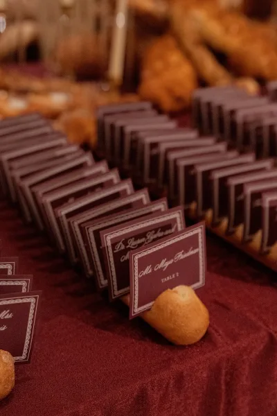 Escort card display featuring wedding escort cards tucked into bread rolls beside stacked bread loaves.