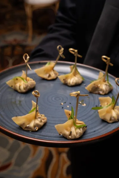 Wedding appetizers served as cocktail hour bites on a ceramic serving tray, inviting guests to pick up each neatly prepared morsel.