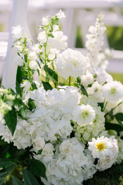 Ceremony aisle flowers styled as a white aisle floral arrangement, featuring white roses in low, ground-level clusters for a romantic walkway.