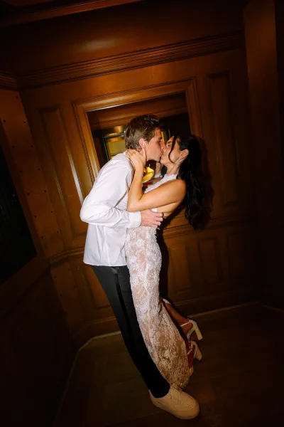 Wedding kiss portrait during a dip kiss as the bride is swept back by the groom, her platform heels peeking out in a candid indoor moment.