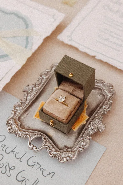 Engagement ring diamond solitaire ring in a velvet box on an ornate silver tray with envelopes and handwritten note on tabletop stationery