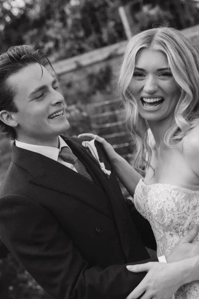 Couple portrait in a black and white wedding portrait, bride and groom laughing on stone garden steps amid lush greenery