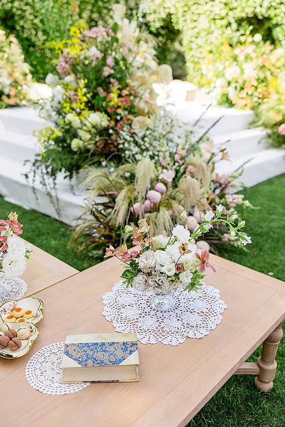 Ceremony aisle decor with outdoor ceremony aisle flowers lining a white runner, pampas grass and greenery on a sunlit garden lawn