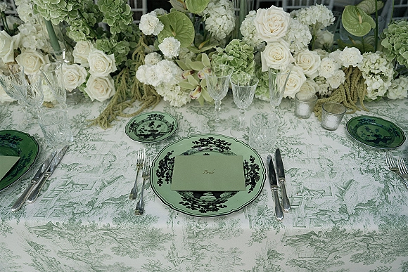 Reception tablescape with green wedding tablescape details—green toile tablecloth, floral china, crystal glassware, votive candles, and hydrangea runner