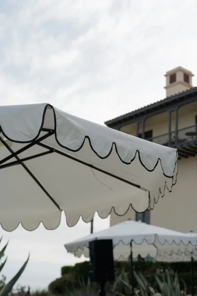 Outdoor event tent with a white canopy tent and scalloped black-trim valance, set beside a building under a cloudy sky