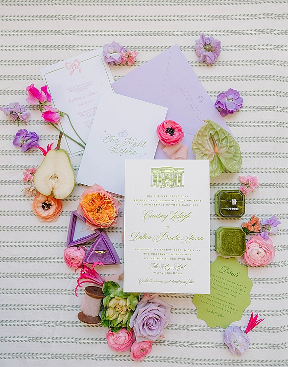 Invitation suite wedding invitation flat lay with lavender envelope, wax seal, velvet ring boxes, pear half and florals on striped fabric backdrop